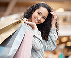 Portrait beautiful mixed race woman standing in a mall while out on a shopping spree. Young hispanic woman carrying bags, spending money, looking for sales and getting in some good retail therapy