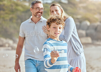 Buy stock photo Boy, bubbles and fun in vacation, parents and break in beach for family, bonding and fun for child. Outdoor, man and woman with smile for kid, proud and travel with youth in nature, mother and dad