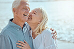 A happy mature caucasian couple enjoying fresh air on vacation at the beach. Smiling retired couple hugging and embracing while bonding outside together