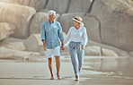 A happy mature caucasian couple enjoying fresh air on vacation at the beach. Smiling retired couple getting a cardio workout while walking outside