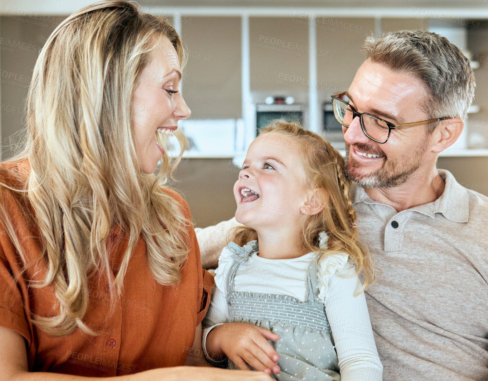 Buy stock photo Home, parents and daughter in living room, smile and bonding with conversation, girl and family on couch. Lounge, talking and relax with child, father and mom in house, glasses and love for kid