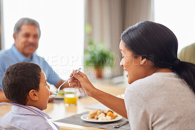 Buy stock photo Family, food and mother feeding son at dining room table in home for meal or social gathering. Breakfast, eating and help with happy people in apartment together for bonding, diet or nutrition