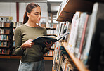 Black woman reading book in a library for education, studying and research in school, university or college campus. Focus, book and student at bookshelf for language learning or philosophy knowledge