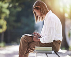 Woman, writing and student with books at a park outdoor to study for future in business management. Studying, learning and knowledge of a young female person in nature to focus on school education