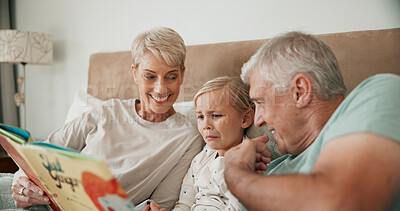 Buy stock photo Grandparents, girl and reading a fairytale story, literature and scary book for bonding at sleepover. Home, grandchild and people together for love, language and grandma or grandpa for spooky fiction