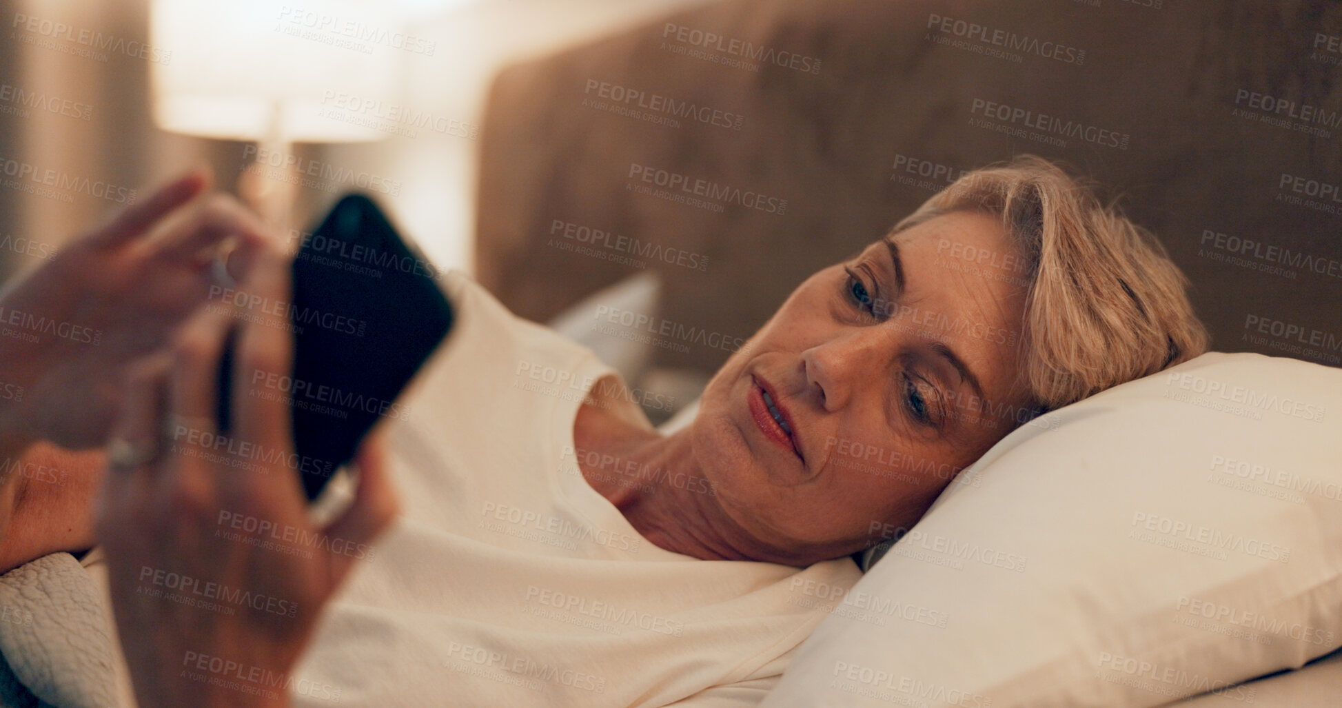 Buy stock photo Reading, bed and senior woman with phone for online blog on insomnia, sleep apnea or relaxing. Communication, night and mature female person networking with email on smartphone in bedroom at home.