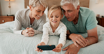 Buy stock photo Grandparents, playing and mobile phone with grandchild in bedroom for growth, development and gaming in home. Girl, happy and tech for learning, joy and fun as youth, kid or young person with bonding