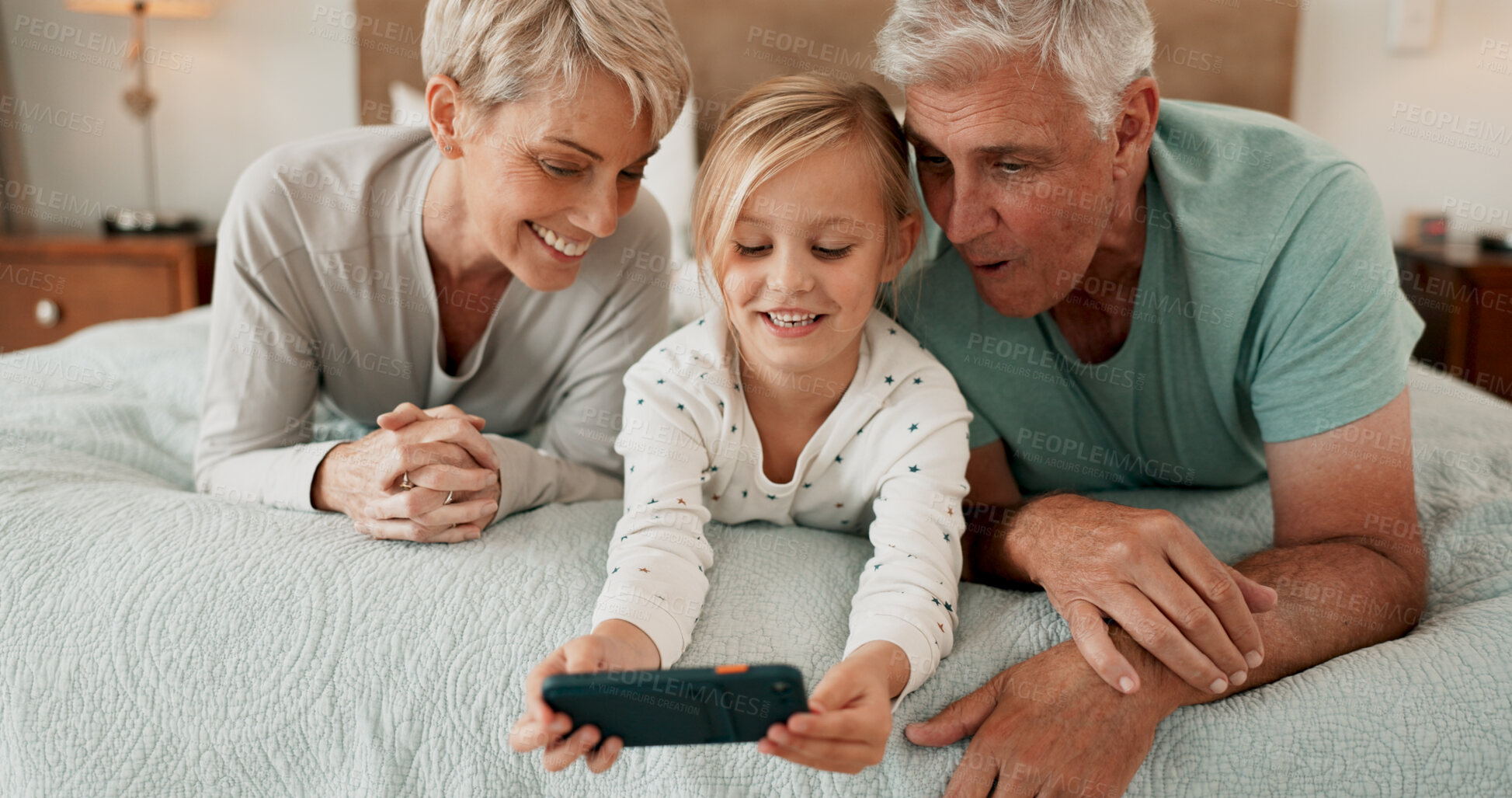 Buy stock photo Grandparents, playing and mobile phone with grandchild in bedroom for growth, development and gaming in home. Girl, happy and tech for learning, joy and fun as youth, kid or young person with bonding