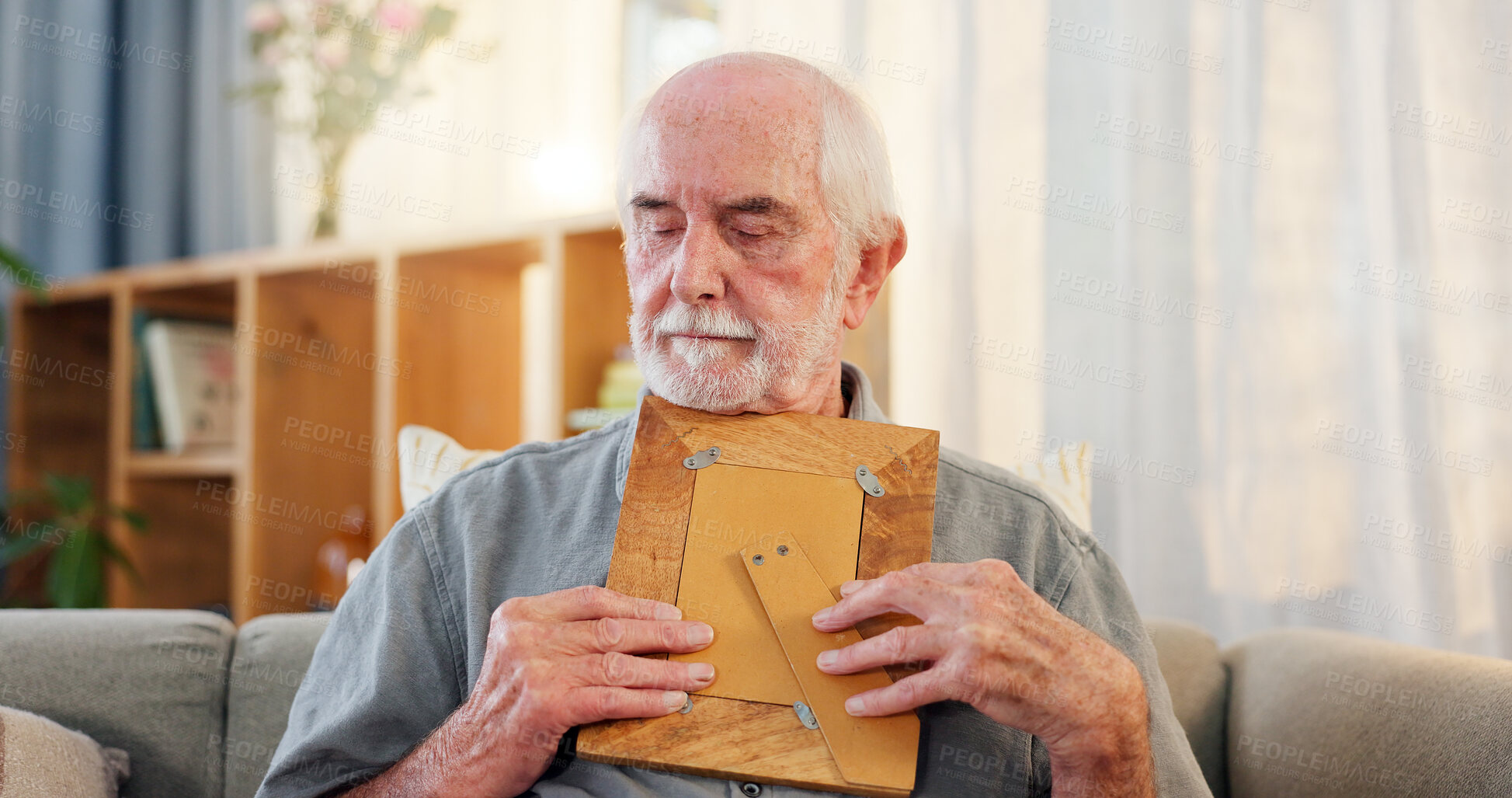 Buy stock photo Memory, senior man and thinking with picture frame for nostalgia, remember and sad in home. Retirement, past and hug photo of missing person with grief, lonely and depression on sofa in living room