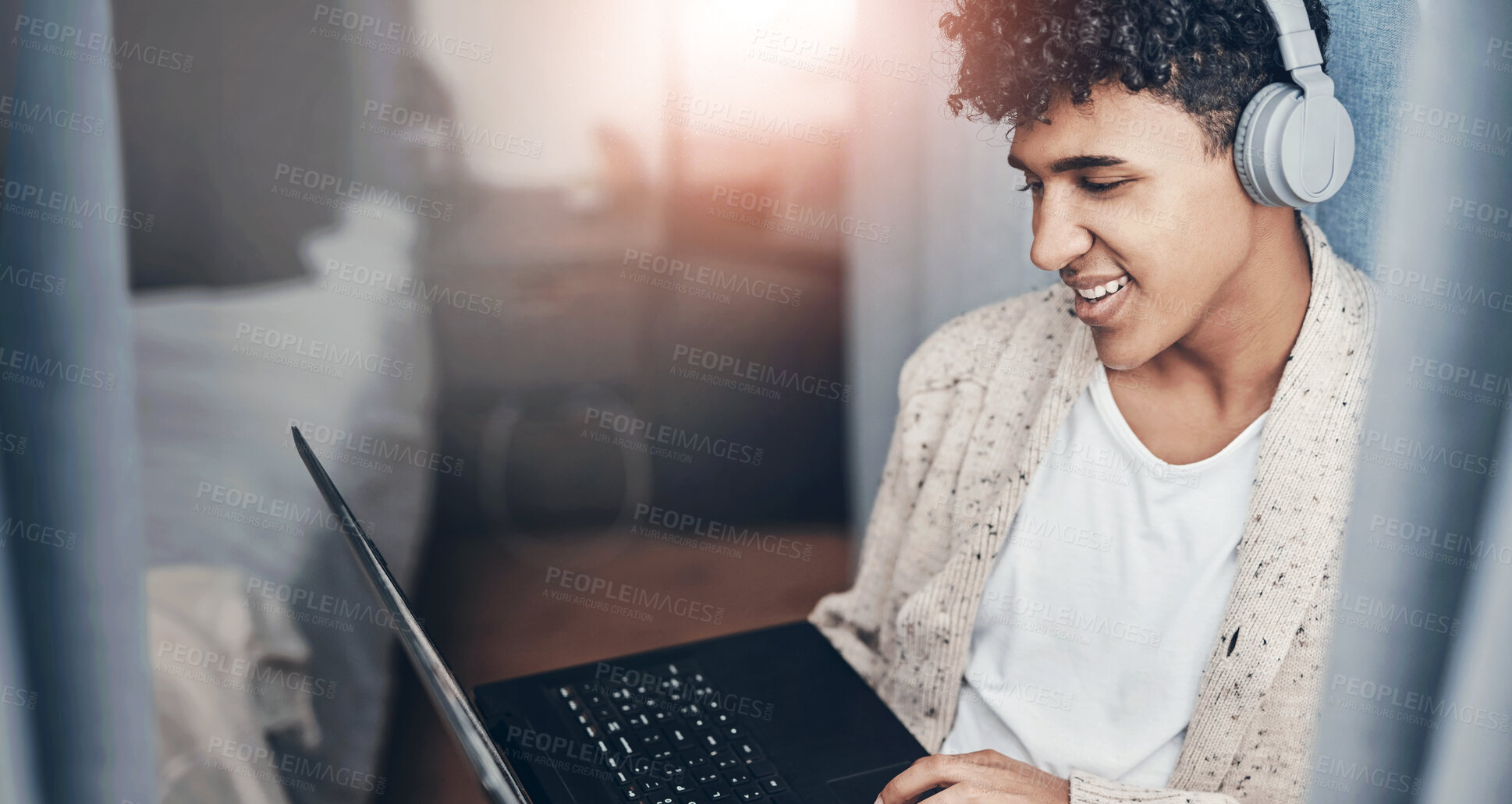 Buy stock photo Shot of a young man using a laptop and headphones at home