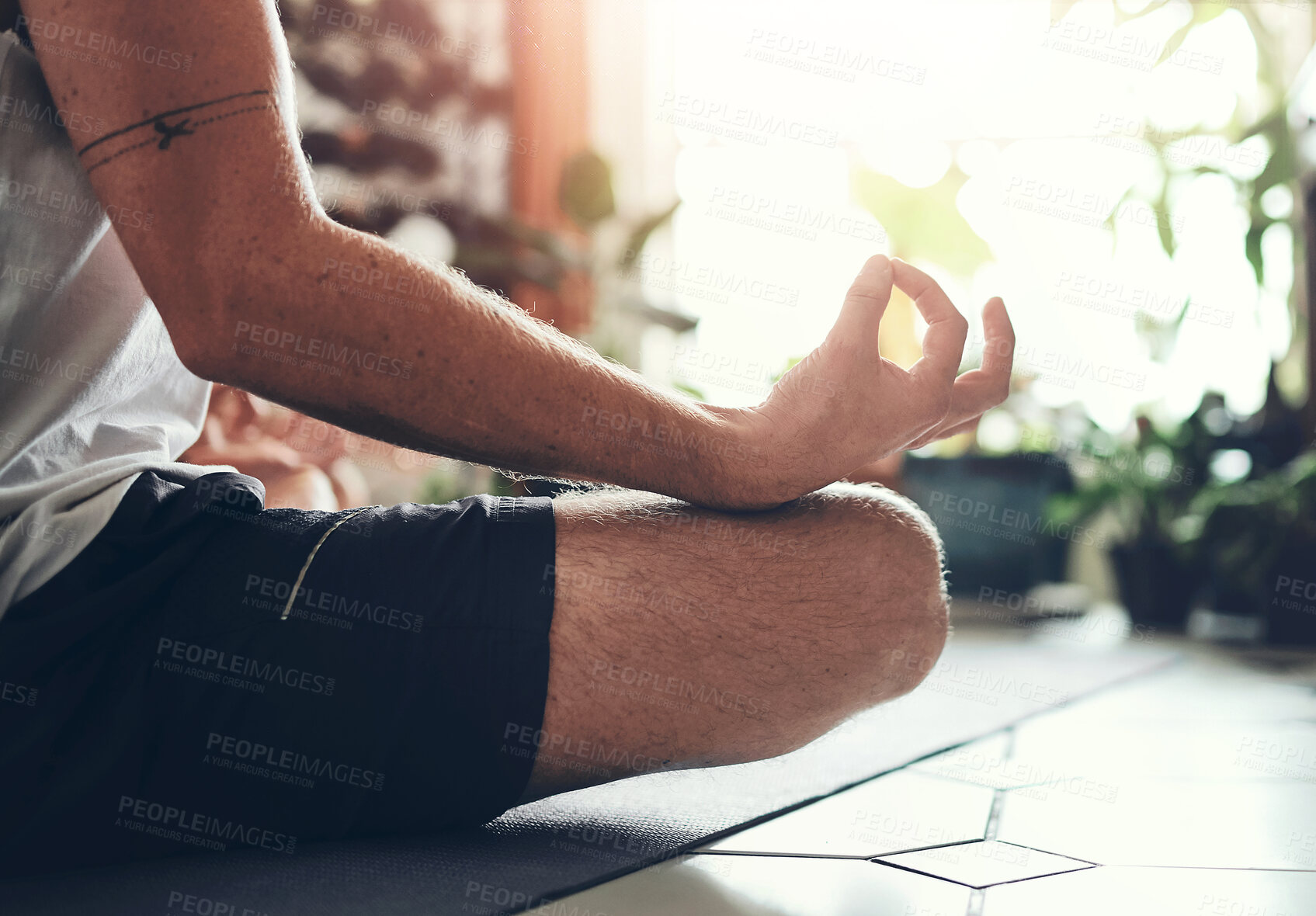 Buy stock photo Shot of an unrecognisable man meditating in the lotus position at home