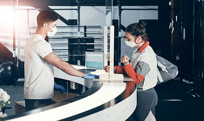 Buy stock photo Shot of a young woman filling in paperwork at the reception desk of a gym