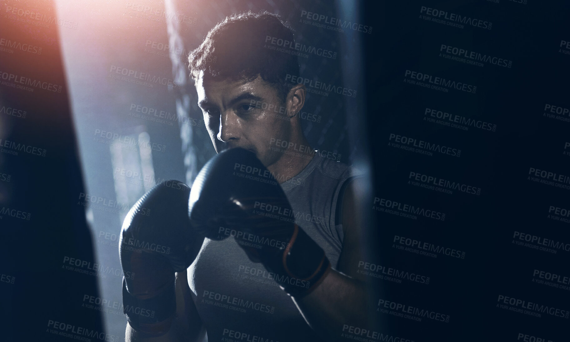 Buy stock photo Shot of a young man practicing his boxing routine at a gym