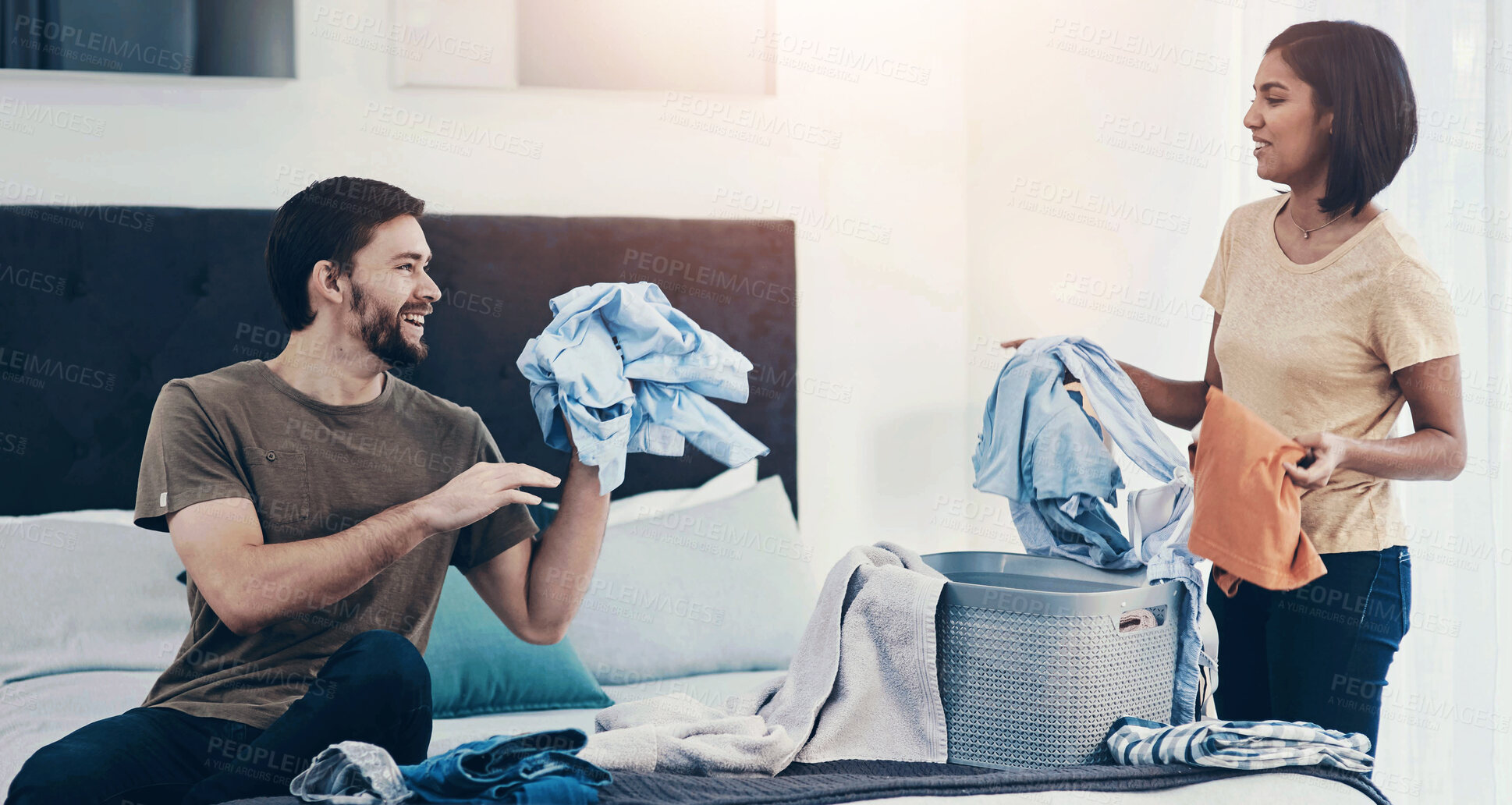 Buy stock photo Couple, happy and laundry on bed with help, support and shared chores for responsibility in home. Happy man, woman and clothes in bedroom for spring cleaning, sorting or routine housework on weekend