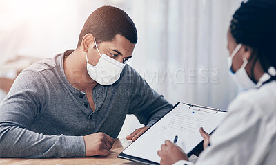 Buy stock photo Shot of a young man going through paperwork during a consultation with a doctor