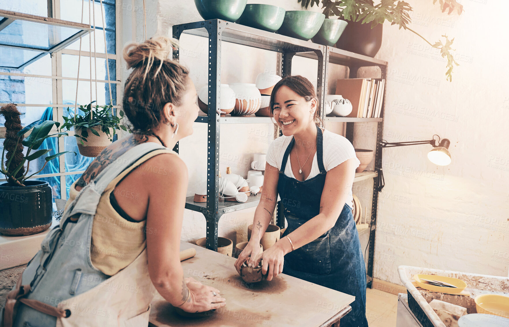 Buy stock photo Shot of two young women kneading clay in a pottery studio