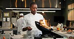 Black man, chef and fire with frying pan in kitchen at restaurant for fine dining, meal and creativity. Employee, professional and cooker with food for culinary, hospitality and catering service