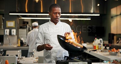 Buy stock photo Black man, chef and fire with frying pan in kitchen at restaurant for fine dining, meal and creativity. Employee, professional and cook with food for culinary, hospitality and catering service