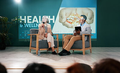 Speaker, health seminar and speech of woman on stage with host on mic and tablet at event. Workshop, talk and conference presentation on wellness, medicine or medical innovation of drugs with guest