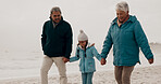 Grandparents, child and beach with holding hands, happy and together on vacation by the sea. Love, smile and happy girl with senior people outdoor in winter on holiday with retirement and travel