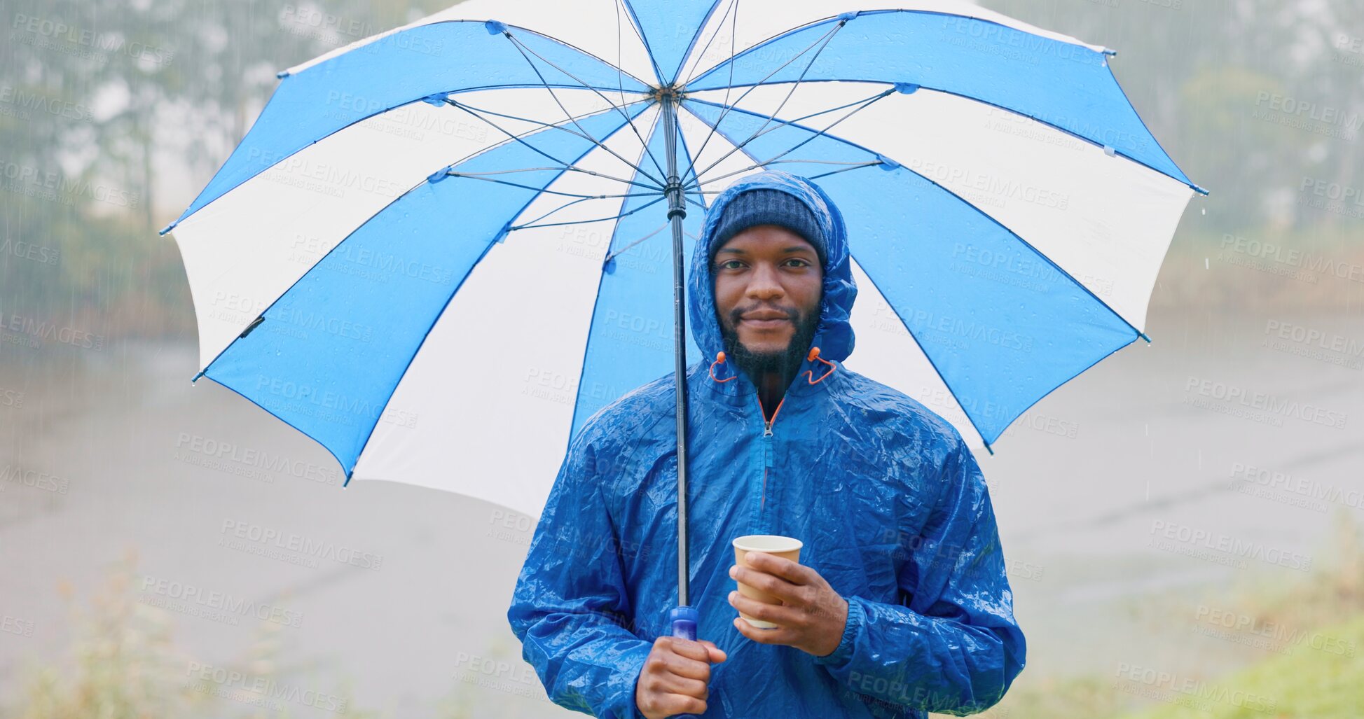 Buy stock photo Black man, portrait and raincoat with umbrella in nature for winter season, hiking or outdoor travel. Young African or male person with coffee, waterproof jacket and shade for trekking on rainy day