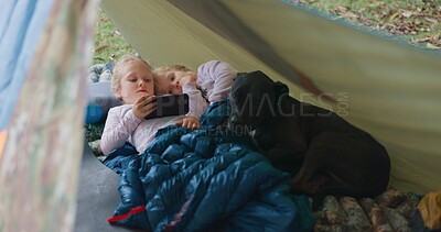 Buy stock photo Children, relax and phone for camping outdoor with watching movies, bonding and streaming videos in nature. Family, girl and mobile in tent of communication, online entertainment or sibling adventure