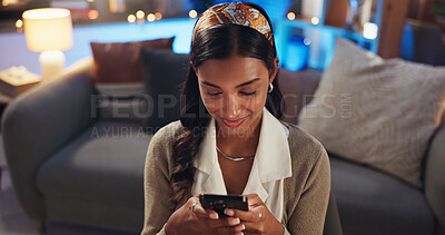 Buy stock photo Happy, night and Indian woman with phone in home for online dating, communication and networking. Relax, smile and person on smartphone for social media, website and internet chat in living room