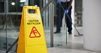 Caution, sign and cleaning for floor, janitor and hygiene service and dark at night in office. Mop, job and disinfection with equipment with warning and male person, disinfectant and wet ground 