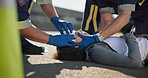 Paramedic, accident and hands on head injury on road in car crash emergency with healthcare help, EMS, wrapping bandage or first responder with victim or rescue in street for transport to hospital