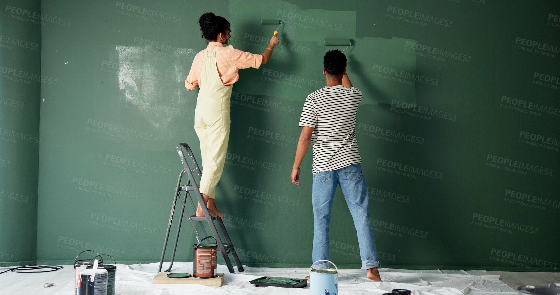 Buy stock photo Couple, people and house wall or painting, roller and home renovation or together in new apartment. Teamwork, property project and diy or make over for relationship, love and back view with care