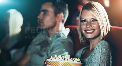 Buy stock photo A young girl eating popcorn while watching a movie at the cinema with her boyfriend