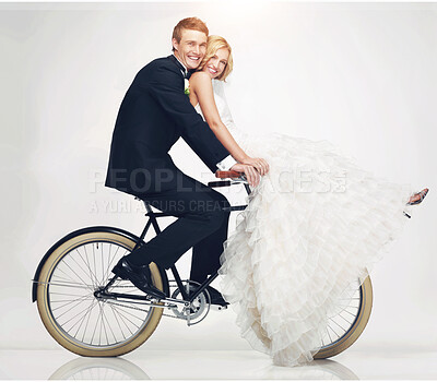 Buy stock photo Studio shot of a newlywed couple riding an old bicycle