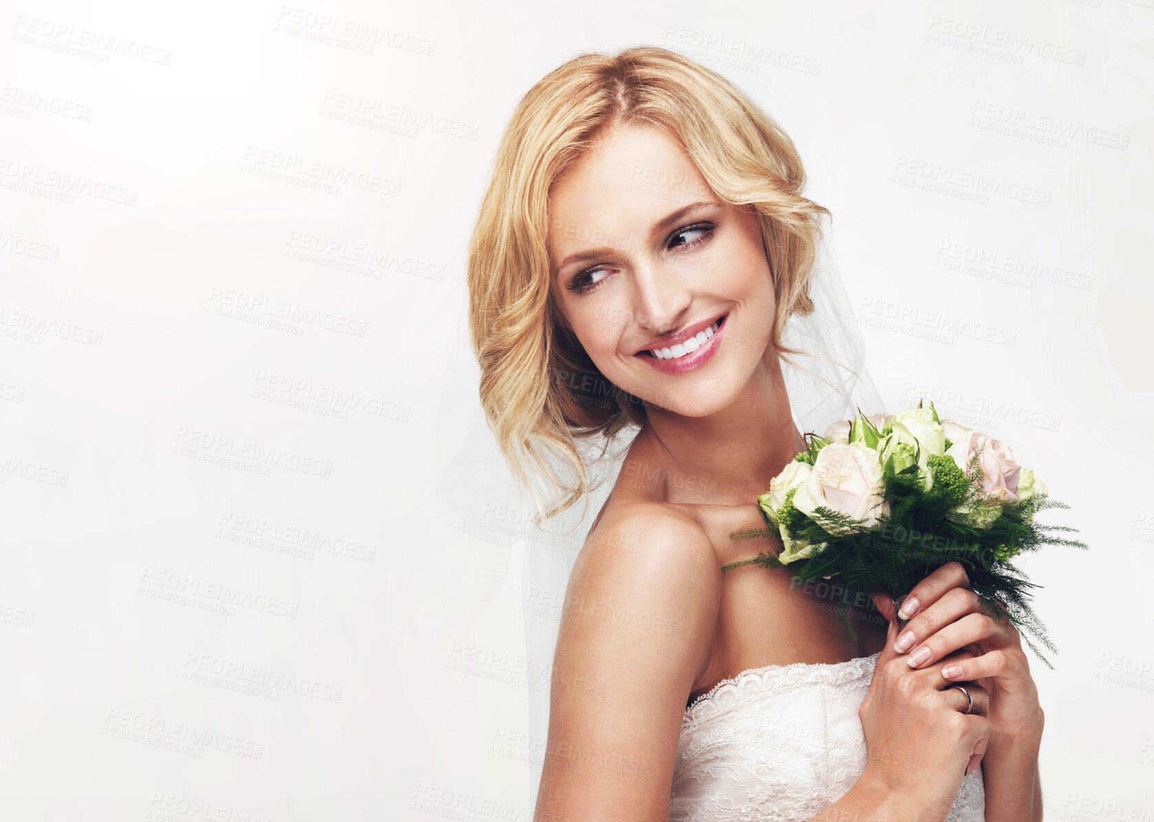 Buy stock photo Young bride holding her bouquet with a sweet smile