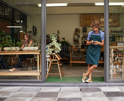 Buy stock photo A handsome young store owner standing in the entrance of his shop