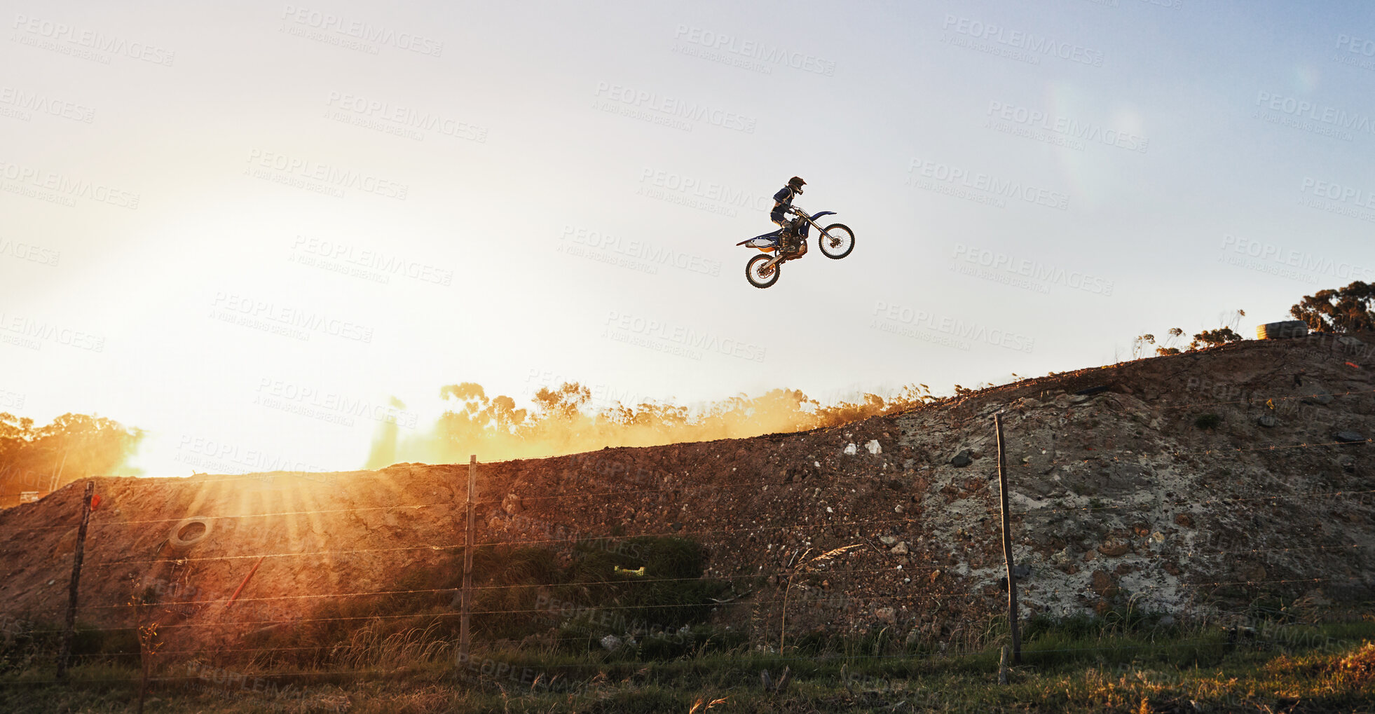 Buy stock photo Shot of a motocross rider going over a jump during a race