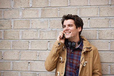 Buy stock photo Man, phone call and wall in city with smile, chat and listening for conversation with mobile connection. Person, smartphone and college student with contact, happy or outdoor on metro street in Italy