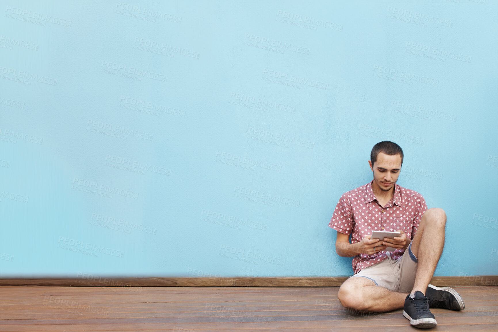 Buy stock photo Male student, sitting on floor and tablet for video streaming, mobile learning or virtual entertainment indoor. Young man, relax and tech for online internet and social media on break with mockup 