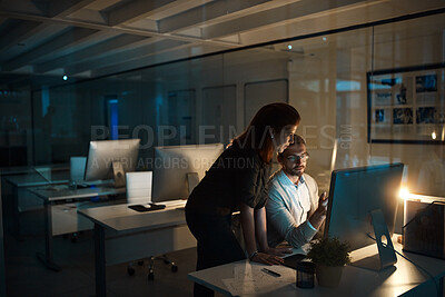 Buy stock photo Shot of two businesspeople working late on a computer in an office