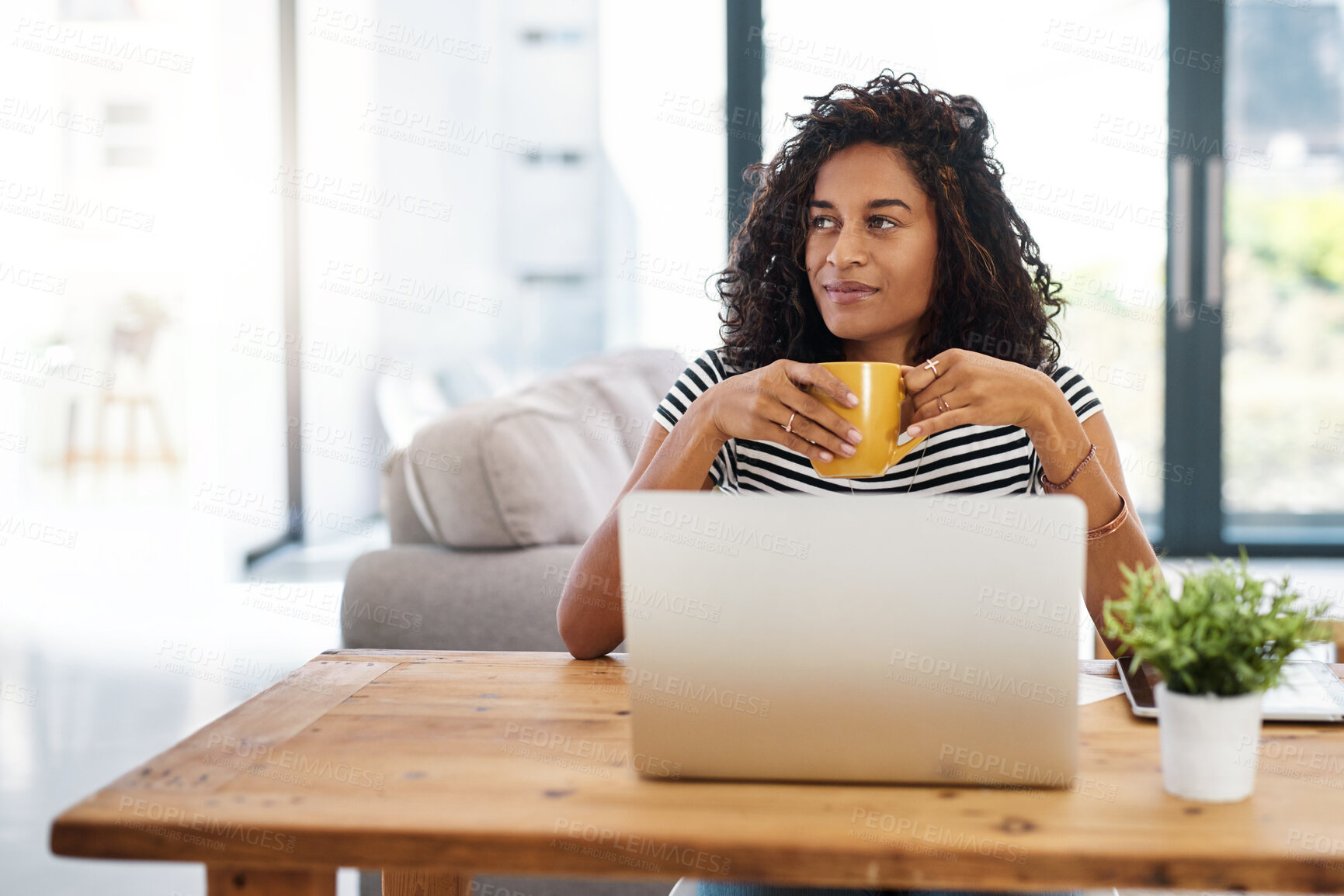 Buy stock photo Cropped shot of an attractive young businesswoman sitting and looking contemplative while holding a cup of coffee in her home