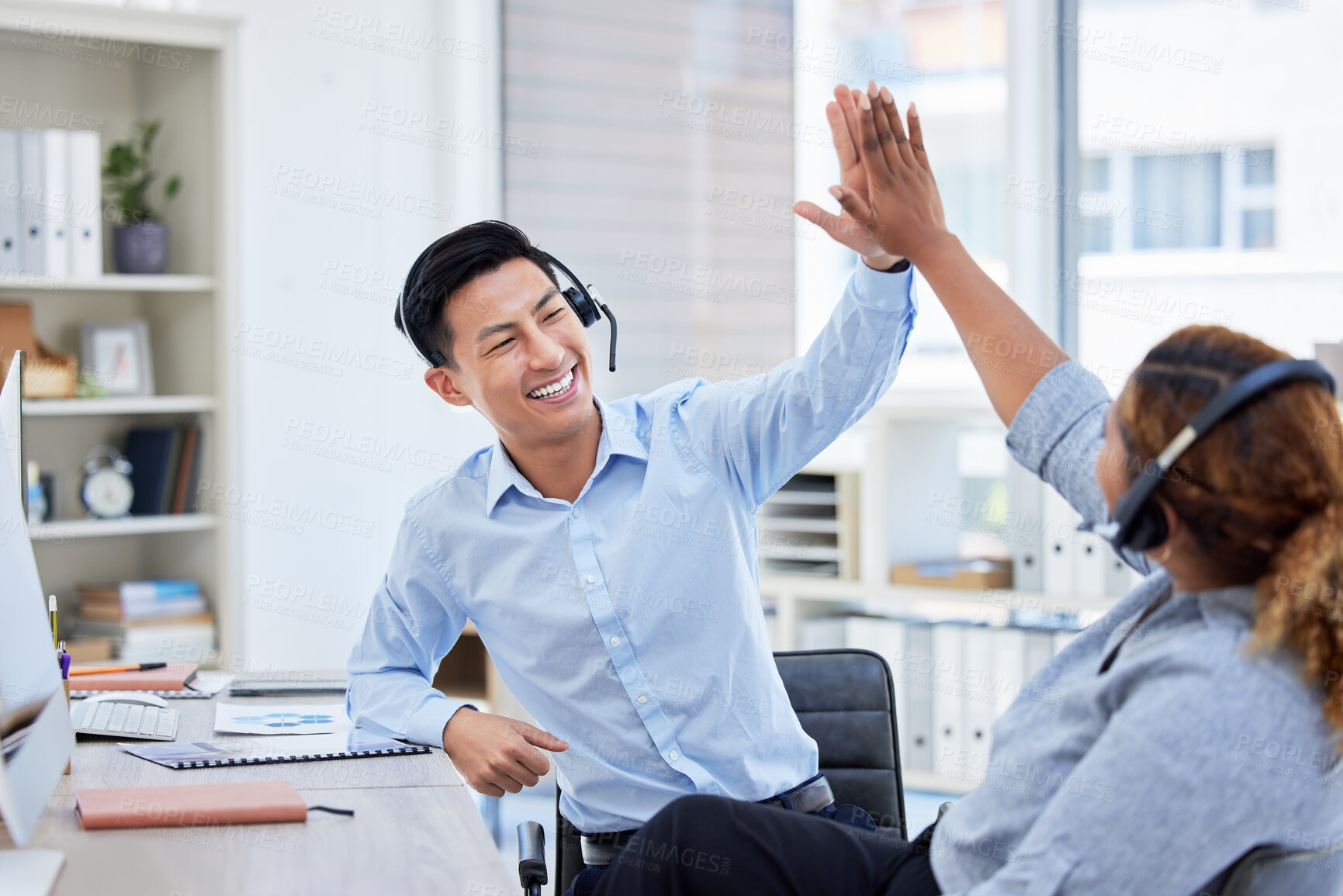 Buy stock photo Call center, high five and team celebrate success at desk with headset for telemarketing teamwork. Asian man and a woman agent excited for sales deal, customer service, bonus achievement and target