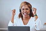 Young happy and excited mixed race businesswoman cheering in support while working on a laptop and wearing a headset alone in an office at work. One hispanic female boss smiling while celebrating success and victory