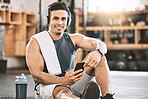 Portrait of happy trainer in the gym. Strong, fit man listening to music after a workout. Strong bodybuilder taking a break from exercise class. Smartphones and music are needed when training