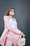 Portrait of a young trendy and confident mixed race woman looking stylish while posing and holding a bag. Hispanic woman chilling in the city and chewing gum 