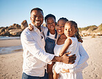 Portrait of a happy african american family with two children standing together on the beach. Loving mother and father carrying their daughter and son while spending time together on vacation