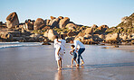 Happy young african american family with two children spending time together and having fun at the beach getting their feet wet. Loving parents enjoying family vacation with little daughter and son