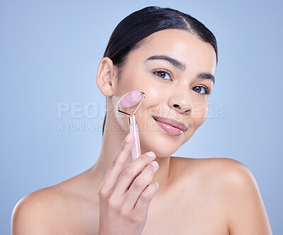 Buy stock photo Skincare, face roller and portrait of woman in studio with lymph drainage massage routine. Beauty, rose quartz and person with crystal tool for facial blood circulation with glow by blue background.