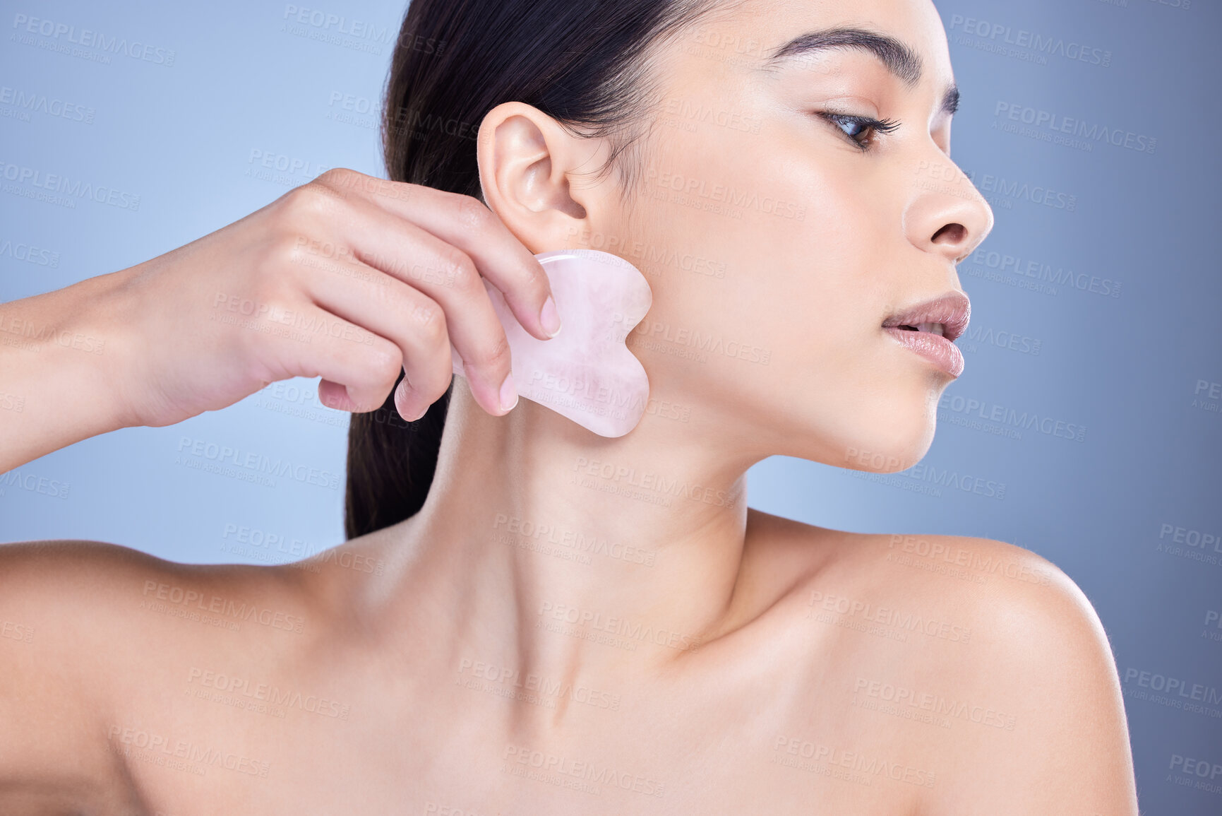 Buy stock photo Beauty, gua sha and woman in studio for skincare lymphatic drainage massage routine for slimming. Natural, rose quartz and person with crystal tool for blood circulation facelift by blue background.