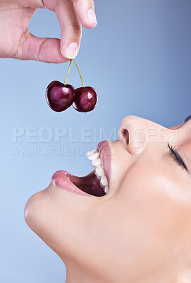 Buy stock photo Woman, smile and eating cherry in studio with closeup for healthy nutrition, digestion and benefits. Mouth, happy and female person with fruit on blue background for antioxidants, detox and vitamin c