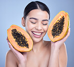 A happy smiling mixed race woman holding a papaya. Hispanic model promoting the skin benefits of a healthy diet against a blue copyspace background