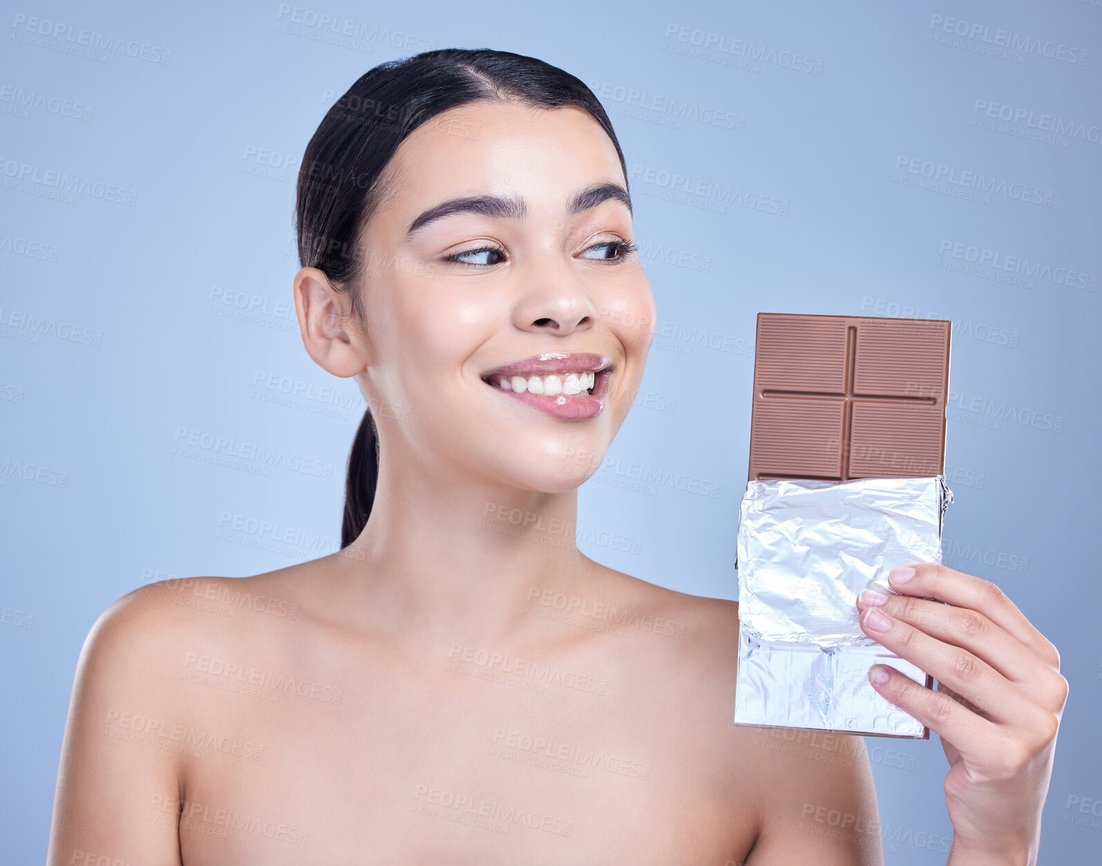 Buy stock photo Skincare, smile and woman with chocolate bar and sweets in studio isolated on blue background. Makeup, beauty and model eating cocoa candy for diet, cosmetics and unhealthy sugar food for diabetes